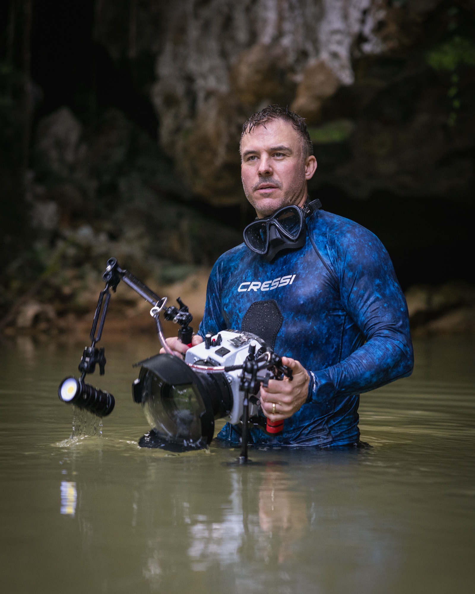 Tom Nagel walking out of the water carrying an underwater camera housing